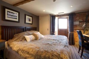 a bedroom with a bed and a desk and a window at The Woolpack Inn in Brown Candover
