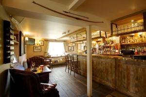 a bar in a restaurant with a counter and chairs at The Woolpack Inn in Brown Candover