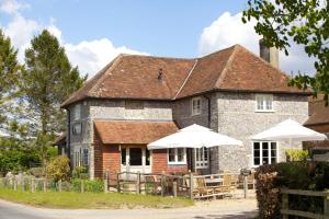 een gebouw met tafels en parasols ervoor bij The Woolpack Inn in Brown Candover