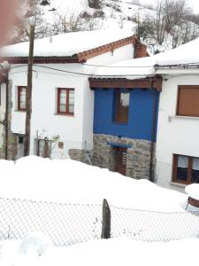 una casa con una puerta azul en la nieve en La Cuadrina de Anton, en Pajares