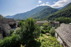 un pueblo en las montañas con árboles y casas en Hotel Garni Maggia en Coglio