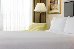 a bedroom with a white bed with a lamp and a chair at Holiday Inn Manchester Airport, an IHG Hotel in Manchester