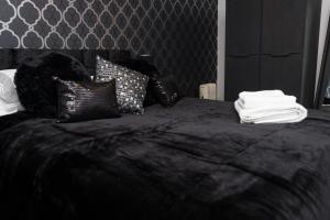 a black bed with black and white pillows on it at Hullidays - Theatre Side Apartment - Refurbished 2023 in Hull