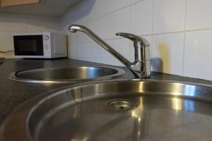 a stainless steel sink in a kitchen with a microwave at Hullidays - Theatre Side Apartment in Hull +32 photos