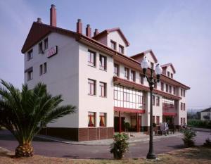 - un grand bâtiment blanc avec un éclairage de rue devant dans l'établissement Hotel Piedra, à Perlora
