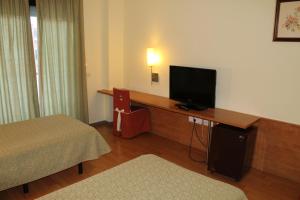 a hotel room with a bed and a television on a desk at Hotel Flora Parc in Castelldefels