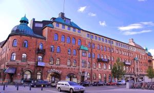 a large red brick building with cars parked in front of it at Järnvägshotellet in Gävle