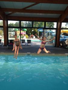 two young girls jumping into a swimming pool at Camping la Haie Penée **** in Saint-Quentin-en-Tourmont
