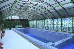 a large swimming pool with a glass roof and an indoor swimming poolvisor at Nurafshon Boutique in Bukhara