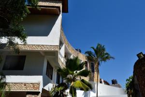 un bâtiment blanc avec un palmier à côté dans l'établissement Serene Hotel, à Dar es Salaam