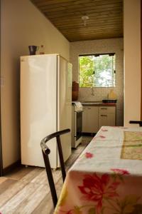a kitchen with a white refrigerator and a table in it at Casa tranquila perto da Joaquina in Florianópolis