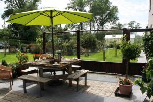 a picnic table with an umbrella on a patio at 't Leeg Huys in Lo-Reninge