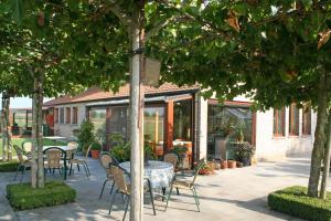 a patio with tables and chairs under trees at 't Leeg Huys in Lo-Reninge