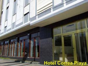 un edificio de playa esquinero con ventanas de cristal en Hotel Correa Playa en San Clemente del Tuyú