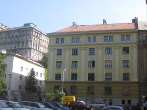a large yellow building with cars parked in a parking lot at Schieszl Apartments 1 in Budapest
