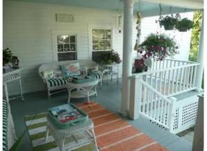 un porche con sillas y mesas en una casa blanca en Topsides Bed & Breakfast, en Wolfeboro