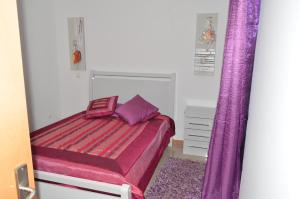 a bedroom with a bed and purple curtains at House Gonçalves in Praia