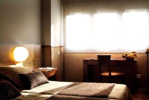a bedroom with a bed and a desk and a window at Hotel Els Caçadors de Ribes in Ribes de Freser
