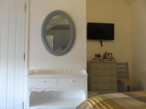 The Golden Mile Country Inn في Ewenny: غرفة نوم مع مرآة على الحائط وخزانة