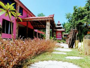 ein Haus mit einem rosa Gebäude und einem Garten in der Unterkunft Bali Suites Itamambuca in Ubatuba
