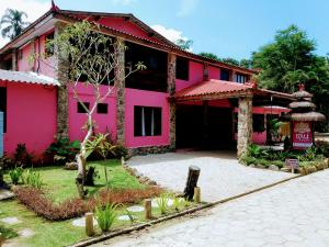 una casa rosa con un cartel delante en Bali Suites Itamambuca, en Ubatuba