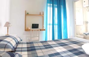 a bedroom with a bed with blue curtains and a television at "A Livanti" B&B in Marzamemi