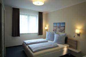 een slaapkamer met een bed met witte kussens en een raam bij Auf dem Blumenhof in Heringsdorf