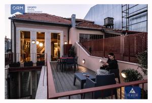 una mujer sentada en el balcón de una casa en ORM - Almada Terrace Apartment, en Oporto