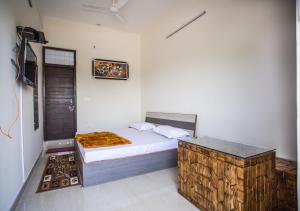 a small bedroom with a bed and a table at Hotel Shiv Kripa in Dehradun