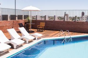 uma piscina com cadeiras e um guarda-sol num telhado em Aruá Hotel em Presidente Prudente