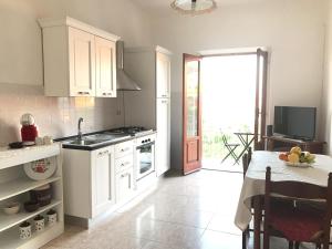 Una cocina con gabinetes blancos y una mesa y un televisor. en Casa Filippo, en Tropea