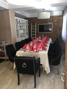 - une grande table avec des chaises noires et des serviettes rouges dans l'établissement Chalet Alpina, à Moroeni