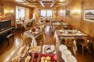 a dining room with wooden tables and a piano at Hotel Aquila in Cortina dʼAmpezzo