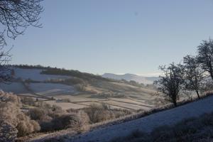 a snow covered hillside with trees and fields at The Tanners Arms in Devynock