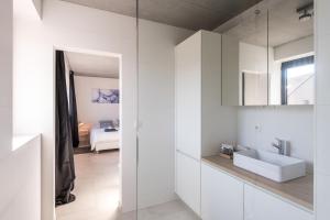 Un baño blanco con lavabo y espejo. en BeHome Dilbeek, en Dilbeek 44 fotos más