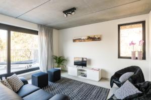 Una sala de estar con un sofá y sillas y un televisor. en BeHome Dilbeek, en Dilbeek