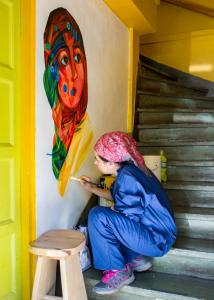 a woman standing in front of a wall next to stairs at Airesbuenos Hostel y Permacultura in Valdivia