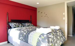 um quarto com uma cama com uma parede vermelha em Central Avenue in the Heart of Oak Bay 26 em Victoria