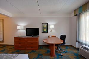 Zimmer mit einem Schreibtisch, einem TV und einem Tisch in der Unterkunft La Quinta by Wyndham Winston-Salem in Winston-Salem
