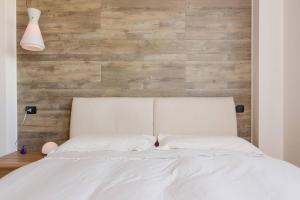 a bedroom with a white bed with a wooden wall at Appartamento Gassman - Holiday Apartment in Milano in Milan