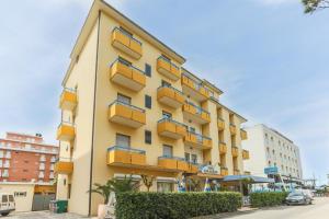 um edifício amarelo com varandas amarelas numa rua em Hotel San Marino em Riccione