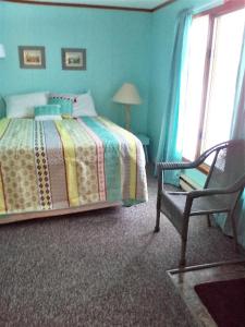 um quarto com uma cama, uma cadeira e uma janela em The Monarch Motel em Cheboygan