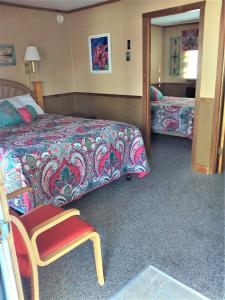 um quarto com uma cama, uma cadeira e um espelho em The Monarch Motel em Cheboygan