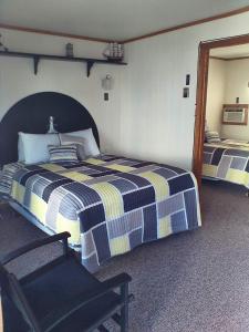 um quarto com duas camas e uma cadeira. em The Monarch Motel em Cheboygan