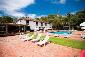 a group of lounge chairs and a swimming pool at Hotel Fazendão in Santa Branca