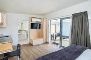 Habitación de hotel con cama y puerta corredera de cristal en Awa Motel, en Whakatane