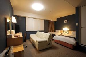 a hotel room with two beds and a couch at Country Hotel Takayama in Takayama
