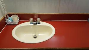 a white sink in a bathroom with a red wall at Red Coat Inn Motel in Fort Macleod