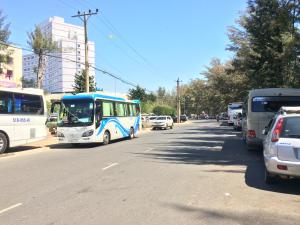 Un autobús azul y blanco conduciendo por una calle con coches en Hanh Huong Hostel, en Phan Thiet