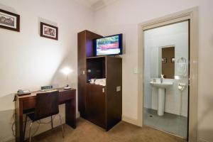 a bathroom with a sink, toilet and a television at Royal Hotel Gympie in Gympie
